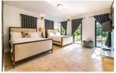 two beds in a bedroom with windows at Luxury Awaits at Casa de Campo A Stunning Five-Bedroom Retreat in La Romana