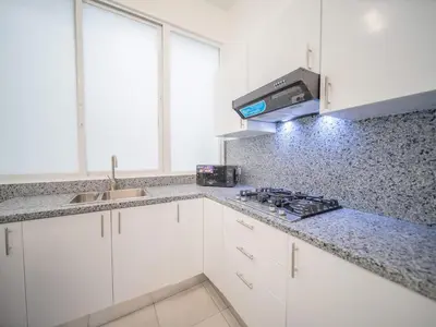 a kitchen with white cabinets and a counter top at Plaza Achim 6B, Modern APT 250m from Sosua beach! in Sosúa