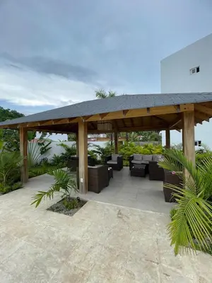 a wooden pavilion with couches and chairs on a patio at 3 bedroom apartment in Armonía Las Terrenas in Las Terrenas