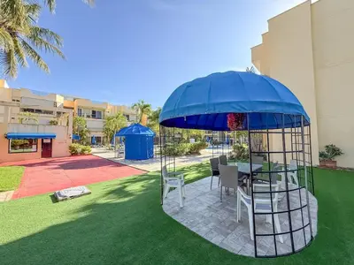 a table and chairs under a blue umbrella in a yard at Garden Condos APT 3 - Affordable 1BR APT in Sosua in Sosúa