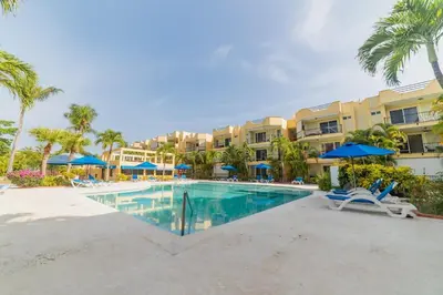 a pool at the resort with chairs and umbrellas at Garden Condos 5 - Ultra Modern Apartment in Sosua in Sosúa