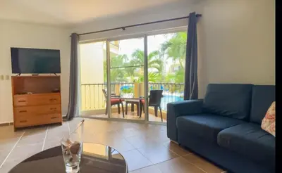a living room with a couch and a television and a table at Garden Condos 10 2BR Apt in Sosua Strip in Sosúa