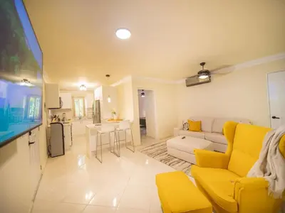 a living room with a yellow couch and a kitchen at Garden Condos 21 Modern 1BR APT in Sosua Strip in Sosúa