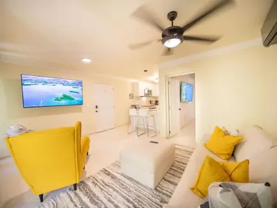 a living room with a yellow couch and a tv at Garden Condos 21 Modern 1BR APT in Sosua Strip in Sosúa