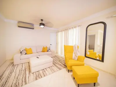 a living room with yellow furniture and a mirror at Garden Condos 21 Modern 1BR APT in Sosua Strip in Sosúa