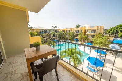 a balcony with a table and chairs and a swimming pool at Garden Condos 35 Best Stylish apartment in Sosua in Sosúa