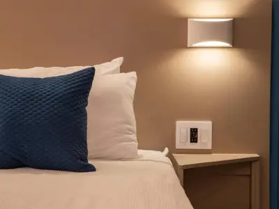 a bed with a blue pillow and a light on the wall at Garden Condos 39 Ultra modern apartment in Sosua in Sosúa