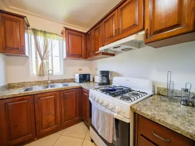a kitchen with wooden cabinets and a stove top oven at Charming 1BR Apt with Pool Walk to Sosua Beach in Sosúa
