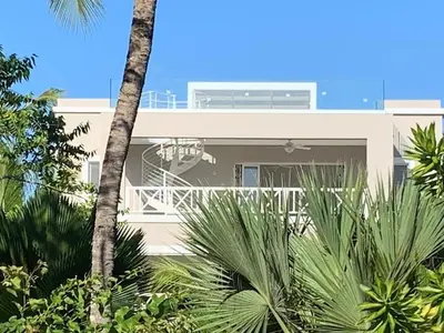 a white house with palm trees in front of it at Luxury Penthouse with roof top & infinitive pool ocean view in Tracadero Beach Club in Bayahibe