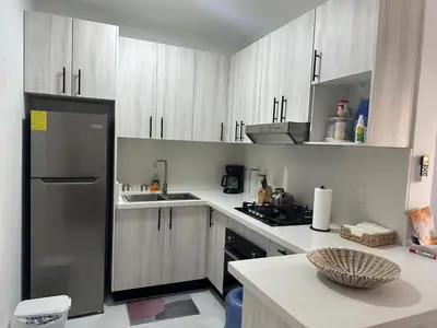 a kitchen with white cabinets and a stainless steel refrigerator at Maravilla Bayahibe , Stylish Apartment, Pool a Wifi in Bayahibe