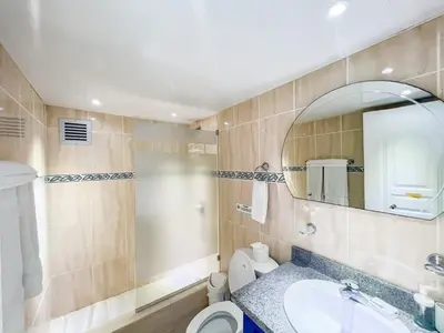 a bathroom with a sink and a toilet and a mirror at Garden Condos 43 Modern Condo in Sosua center in Sosúa