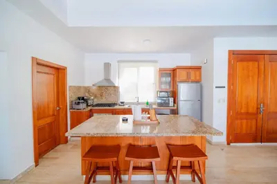 a kitchen with wooden cabinets and a island with chairs at Luxury 2BR Villa next to Santa Fe in Sosúa