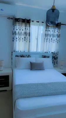 a bedroom with a white bed with white curtains at Appartement lumineux, piscine & plage proche in Punta Cana