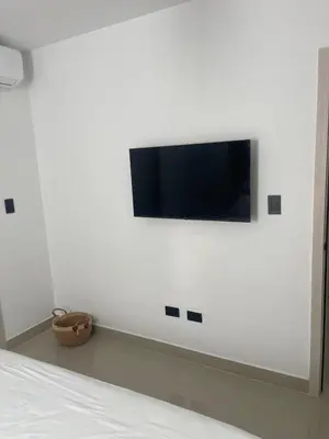 a flat screen tv on a white wall in a bedroom at Appartement lumineux, piscine & plage proche in Punta Cana