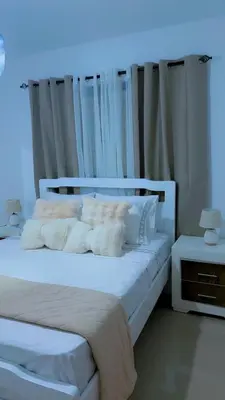 a white bed with white sheets and pillows at Appartement lumineux, piscine & plage proche in Punta Cana