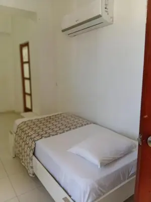 a bed in a room with a white wall at Yuloren Hostal 1 min del monumento & 5 de Agora Mall in Santiago de los Caballeros