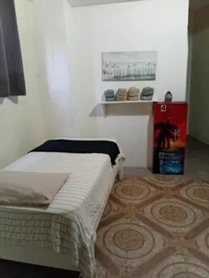 a small bedroom with a bed and a refrigerator at Yuloren Hostal 1 min del monumento & 5 de Agora Mall in Santiago de los Caballeros