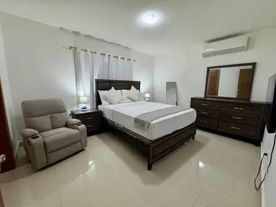 a bedroom with a bed and a chair and a mirror at Modern apartment in Gurabo Santiago in Santiago de los Caballeros