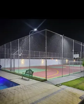 a tennis court at night with a bench on a court at Modern apartment in Gurabo Santiago in Santiago de los Caballeros