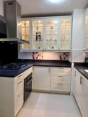a kitchen with white cabinets and black counter tops at Modern apartment in Gurabo Santiago in Santiago de los Caballeros