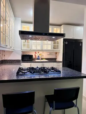 a kitchen with a stove and a counter with two chairs at Modern apartment in Gurabo Santiago in Santiago de los Caballeros