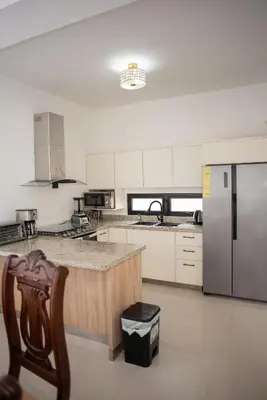 a large kitchen with a refrigerator and a counter at Presmita rose 24 in Punta Cana