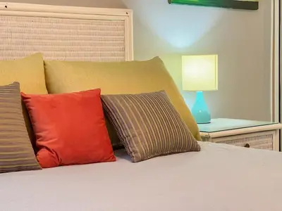 a bed with three pillows and a table with a lamp at Garden Condos APT 44 - Comfy 1BR APT in Sosua in Sosúa