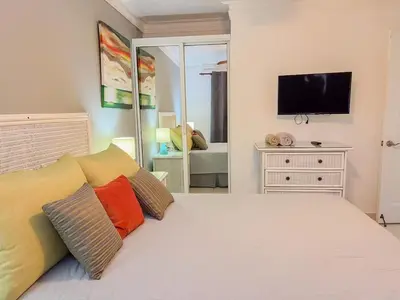 a bedroom with a white bed with pillows and a tv at Garden Condos APT 44 - Comfy 1BR APT in Sosua in Sosúa