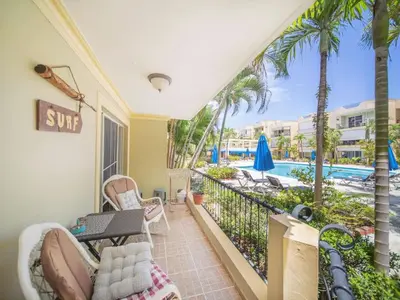 a balcony with a view of a pool and palm trees at Garden Condos 7 - Central Apartment in Strip in Sosúa