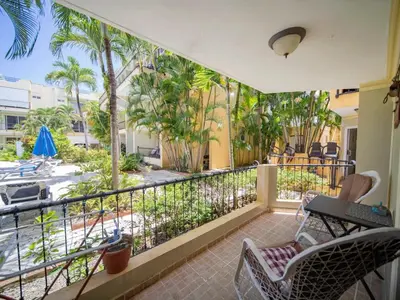 a balcony with a view of a patio with palm trees at Garden Condos 7 - Central Apartment in Strip in Sosúa