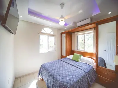 a bedroom with a bed and a tv and windows at CC 3 Casa de Compai Unit 3 Steps to Everything in Sosúa