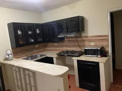 a kitchen with black cabinets and a sink and a microwave at gina apartamento in Monte Llano