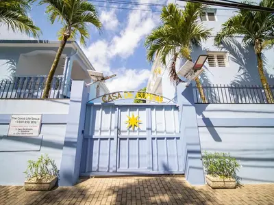 a blue and white house with a gate and palm trees at Casa de Compai Unit 4 Comfort in Central Sosua in Sosúa