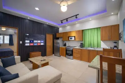 a living room with a couch and a kitchen at 1BR Apt with Pool & Cigar Bar Lounge Casa de Compai in Sosúa