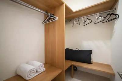 a bathroom with a wooden closet with towels and hangers at 1BR Apt with Pool & Cigar Bar Lounge Casa de Compai in Sosúa