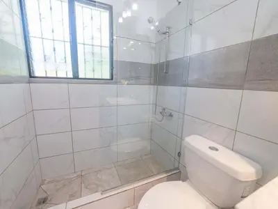 a white bathroom with a toilet and a window at 14 Bedroom Villa 2 mins from Sosua in Sosúa