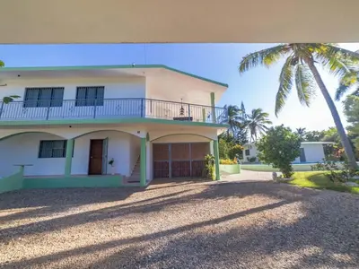 a white house with a balcony and a palm tree at 14 Bedroom Villa 2 mins from Sosua in Sosúa