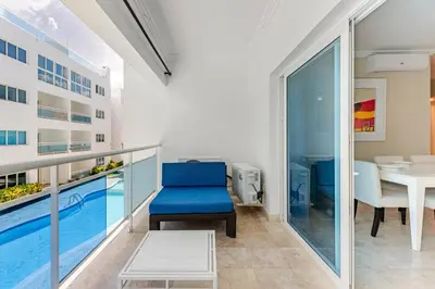 a living room with a blue chair and a pool at Large apartment at the foot of the beach in Punta Cana