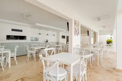 a dining room with white tables and white chairs at Large apartment at the foot of the beach in Punta Cana