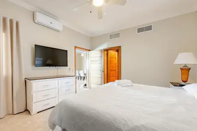 a white bedroom with a large bed and a flat screen tv at Large apartment at the foot of the beach in Punta Cana