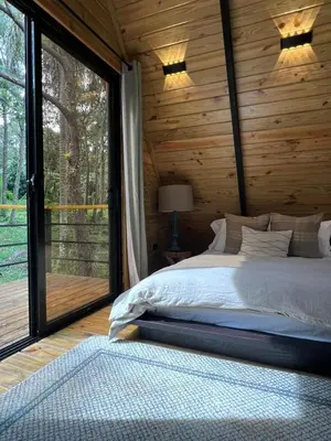 a bedroom with a bed and a large window at Alpina Village, Jarabacoa in Jarabacoa