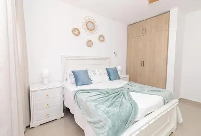 a white bedroom with a bed and a wooden cabinet at Stylish 2BR Apartment in the Heart of Bayahibe in San Rafael del Yuma
