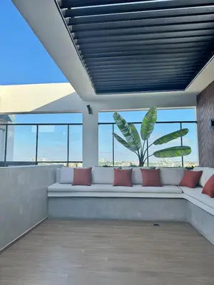 a couch in a room with windows and a plant at Los Corales del Sur- Entire rental unit in Santo Domingo Este, Dominican Republic in Ensanche Savica de Mendoza