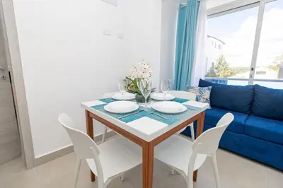 a dining room with a table and chairs and a blue couch at Tropical Studio Getaway in Bayahibe in San Rafael del Yuma