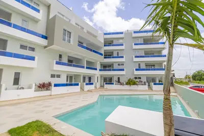 an apartment with a swimming pool in front of a building at Tropical Studio Getaway in Bayahibe in San Rafael del Yuma