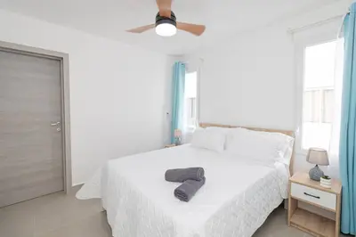 a white bedroom with a bed with two towels on it at Tropical Studio Getaway in Bayahibe in San Rafael del Yuma