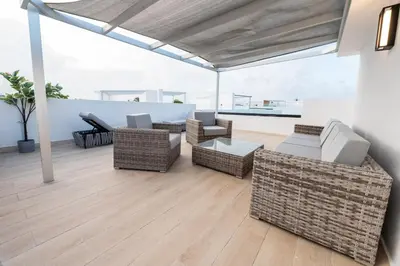 a living room with wicker furniture on a wooden floor at Punta Cana Penthouse Private Picuzzi & Beach Access in Punta Cana
