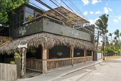 a building with a straw roof with a balcony at Family Villa Terrenas Samana Near the Beach in Las Terrenas