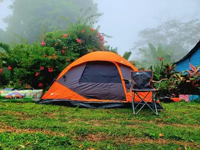 an orange and black tent and a chair in the grass at Casita Linda Playas Rios Wifi Agua HOT AC and more in Paraíso