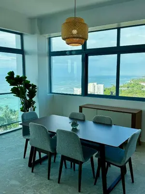 a dining room with a table and chairs and windows at Juan Dolio 2BR Apt Beach front in Juan Dolio